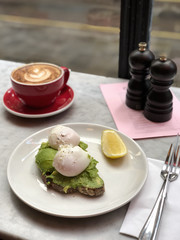 Avocado toast with poached egg and cappuccino, cafe flat lay