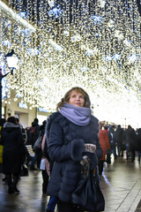 A woman admires the festive illuminations in the city street.