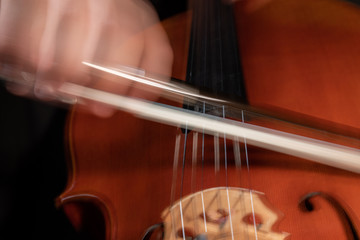 A young cellist practices intensely in this close up high resolution photo of strings, cello, and bow