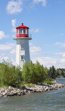 A horizontal photo of a lighthouse situated beside a lake.