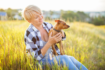 Beautiful ,mature woman with dog outdoor in sunset lights.