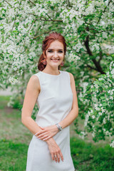 Fototapeta premium Charming woman wearing beautiful white dress under the apple tree