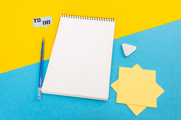 Notepad with pen and clip on yellow blue background