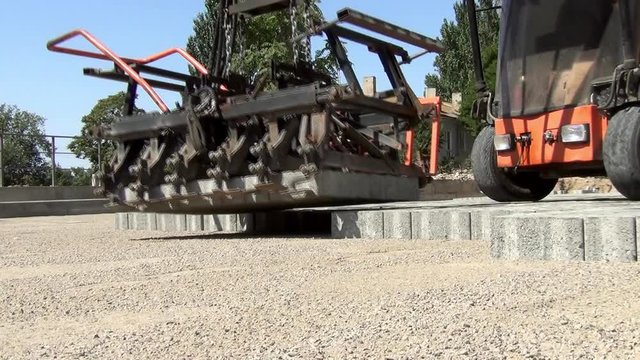the work of a special machine for the automatic laying of several square meters of new paving slabs at the same time in the summer on a sunny day close-up