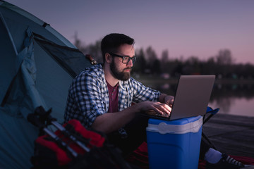 Man working on a laptop computer while camping