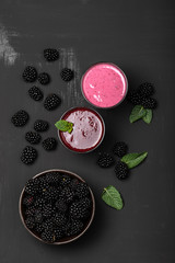 Fototapeta na wymiar Glass of blackberry milkshake and smoothies on black background. Healthy drink. Copy space. Top view.
