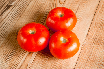 Fresh tomatoes on wooden background. Preparation for the preparation of salad from vegetables. Organic vegetables.