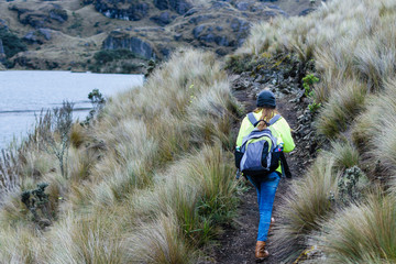 Mujer caminando en montaña junto a laguna