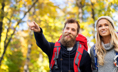 adventure, travel, tourism, hike and people concept - couple of travelers with backpacks over autumn park background