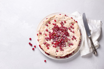 Delicious homemade tart with red currants and meringue, decorated with fresh berries, sprinkled with powdered sugar on a white plate on a light gray background, top view	