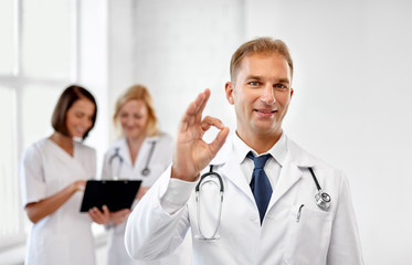 healthcare, medicine and profession concept - smiling male doctor in white coat at hospital showing ok sign