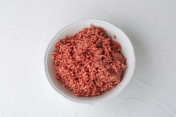 Obraz na płótnie Canvas Raw minced meat in a bowl on a light background. Close-up, top view.