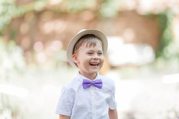 A little boy of 5 years old walks in a flowered park. Lavender. Spring. Portrait of a boy in a hat with a bow tie.