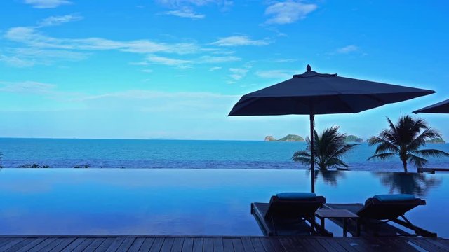 Two deck chairs next to a luxury resort infinity pool in a tropical paradise.