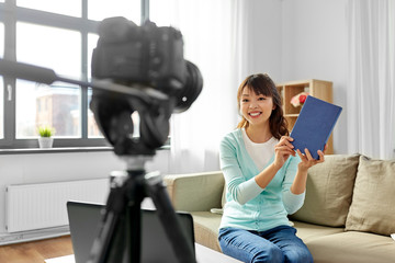 blogging, technology, videoblog and people concept - happy smiling asian woman or blogger with camera recording video blog of book review at home