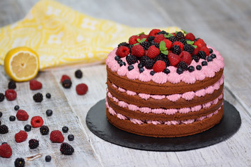 Chocolate cake with berries on wooden background.