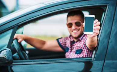 Man sitting in a car and showing blank smartphone screen. Transportation, technology concept