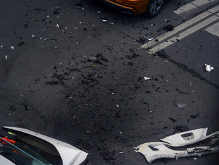 White modern car with a dent and broken bumper after an accident on an empty street surrounded by...
