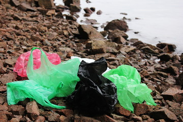 A bunch of reusable, multi-colored plastic bags polluting the environment. Garbage on the seashore.