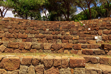 ancient amphitheater, stairs of red and brown stone and rows with threes behind and the
