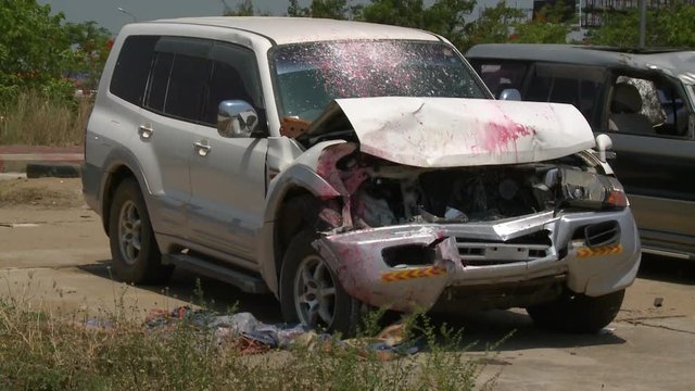 A hand held, medium shot of a white SUV car splashed with red paint, abandoned because it has been involved into an accident.