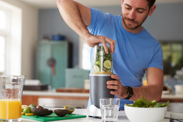 Man Making Healthy Juice Drink With Fresh Ingredients In Electric Juicer After Exercise