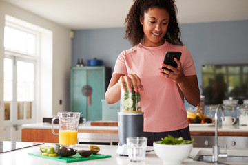 Woman Using Fitness Tracker To Count Calories For Post Workout Juice Drink He Is Making
