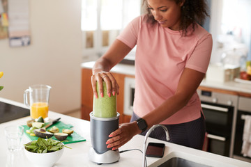 Woman Making Healthy Juice Drink With Fresh Ingredients In Electric Juicer After Exercise