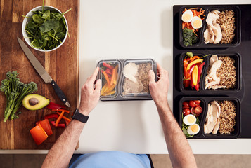 Overhead Shot Of Man Preparing Batch Of Healthy Meals At Home In Kitchen