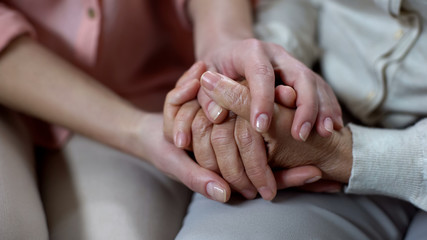 Woman holding mother hands closeup, nursing home support, family love and help