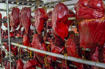 Large chunks of red juicy smoked meat hanging on threads. Delicacy of meat, unusual dainty.