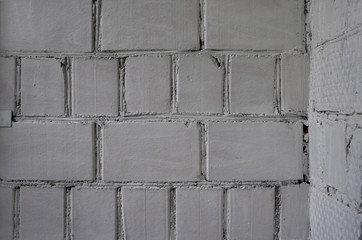  Old whitewashed weathered wall of uneven bricks with internal angle. Natural defects. Closeup. Background texture. Copy space.