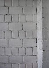  Old whitewashed weathered wall of uneven bricks with internal angle. Natural defects. Closeup. Background texture. Copy space.