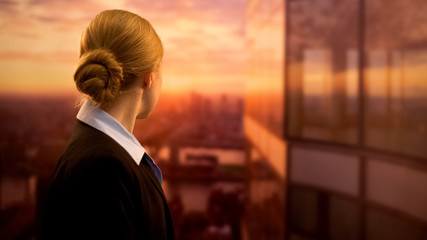 Young business employee looking at sunset, dreaming of successful job career