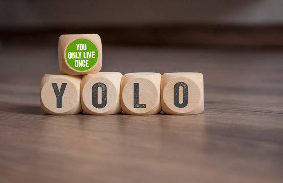 Cubes and dice with YOLO - You only live once on wooden background