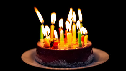 Candles burning out on delicious chocolate cake, isolated on black background