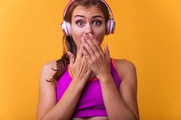 Fototapeta premium Young sport woman covering mouth with hands for saying something inappropriate over isolated yellow background. Teenager sport girl covering mouth with hands