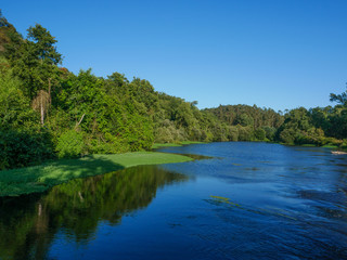 Beautiful summer scene over Ave river in Vila do Conde, Portugal on bright sunny day with blue sky and green trees lining river banks.