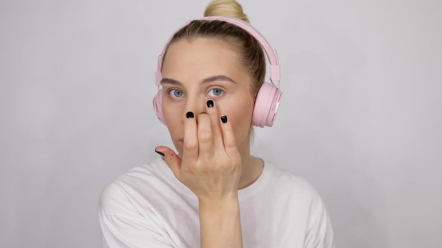 close up beauty blondie woman applying bb cream to her cheeks professional makeup. Beautiful girl in pink headphones applying cosmetic. Tutorial make up fashion industry salon music 5g
