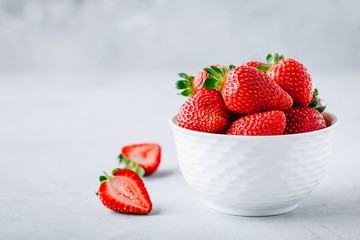 Fresh ripe delicious strawberry in a white bowl on a grey stone background