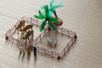 Miniature toy Arab man and wife in abaya buys camel and sheep from a kid on a farm concept.