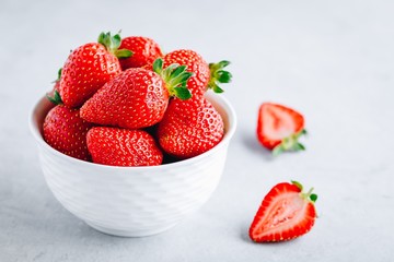 Fresh ripe delicious strawberry in a white bowl on a grey stone background