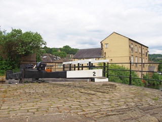 Naklejka premium a close up of wooden lock gates on the calder hand hebble navigation canal in front of the basin in sowerby bridge west yorkshire surrounded by trees and buildings