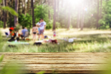 Table background with wooden top board with nice forest and gardens view in distance. Happy barbecue or picnic time with family. Empty space on the table top for an advertising product.. - obrazy, fototapety, plakaty
