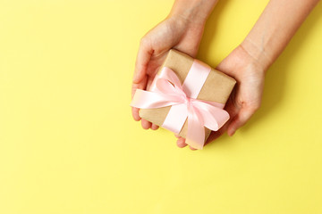 gift in female hands on a colored background top view.