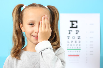 little cute cheerful girl passes an eye test in the office of an ophthalmologist