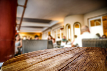 Wooden table top background in the rastaurant. Blurred restaurant view. Wooden top board empty space for an advertising product.