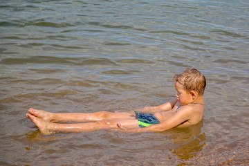a boy of seven years is swimming in the river