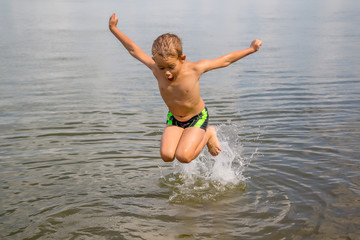 happy boy jumps and flies over the water