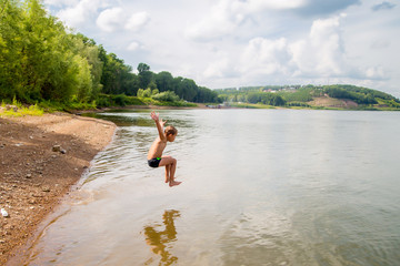 happy boy jumps and flies over the water